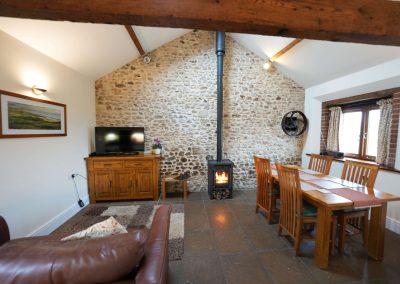 Lovely photo of the Apple Loft including the log burner lit and the table and comfy seating